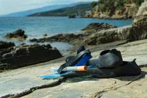 snorkel fins and mask next to the water