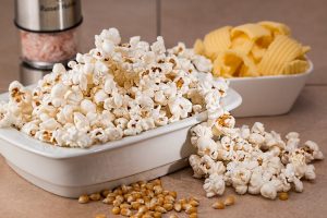 a bowl of popcorn next to a bowl of potato chips