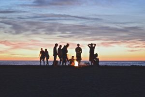 a group of friends in front of the ocean at sunset