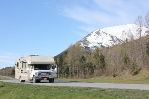 white RV driving on a road with a mountain in the background