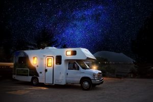 white RV with lights on parked beneath a night sky