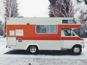 white RV with orange stripe set up at a snowy campground