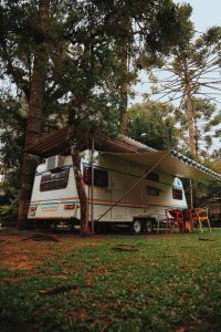 white RV with awning in the woods