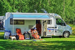 woman sitting and reading in front of a parked RV rental