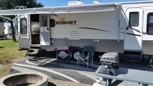 RV rental set up at campground with two chairs in front